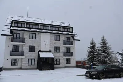 a building with a car parked in front of it at Apartmani Vidik,Treska in Kopaonik