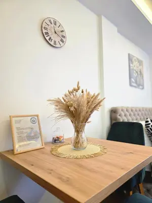 a vase on a table with a clock on the wall at Panoramic Nest in Vrnjačka Banja
