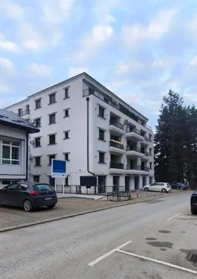 a white building with cars parked in front of it at Studio Georgijev in Vrnjačka Banja