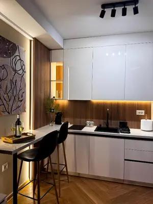 a kitchen with white cabinets and a bar with chairs at Studio Georgijev in Vrnjačka Banja