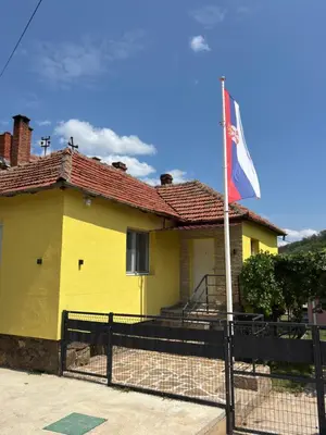 a yellow house with a flag in front of it at Vilasukovo