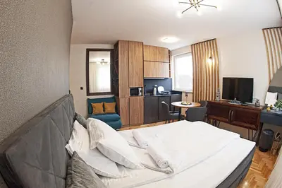 a bedroom with a large bed and a kitchen at Apartmani Kraljevi Čardaci in Kopaonik