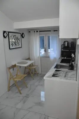 a kitchen with a counter and a table and chairs at Fiko Apartment in Niš