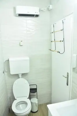 a white bathroom with a toilet and a sink at Fiko Apartment in Niš