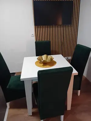 a white table with green chairs and a hat on it at Apartman Đorđevic in Vrnjačka Banja