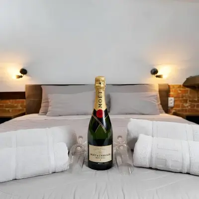 a bottle of wine sitting on top of a bed at Hedonia Luxury Rooms in Pirot