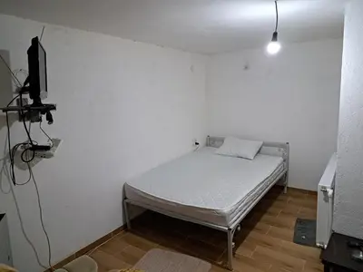 a small bedroom with a bed and a television at Hostel Lalinac in Niš