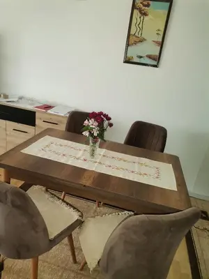 a wooden table with chairs and a vase of flowers on it at Mala Sirena in Pirot
