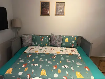 a bed with a green bedspread with animals on it at Apartman Nikolic 417 in Kopaonik