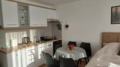 a kitchen with a table and chairs and a small kitchen with white cabinets at Kopaonik Alibi25 in Kopaonik