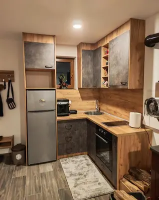 a kitchen with wooden cabinets and a stainless steel refrigerator at Suncani breg in Crni Vrh