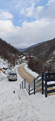 a car parked on the side of a snow covered road at Suncani breg in Crni Vrh