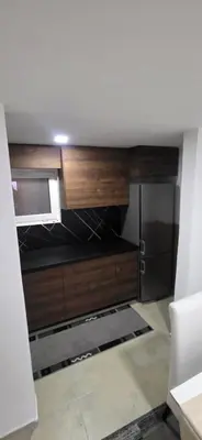 a kitchen with wooden cabinets in a room at Pansion Mima in Niš