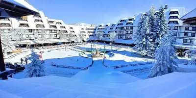 a courtyard covered in snow in front of buildings at Konaci Prime Center in Kopaonik