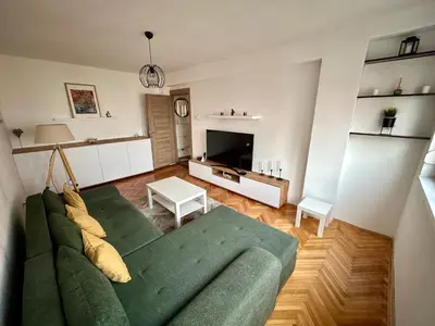 a living room with a green couch and a television at Tilia in Zaječar