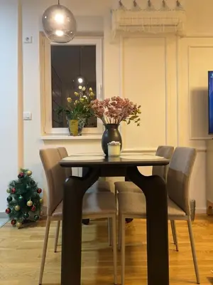 a dining room table with chairs and a vase with flowers at Stan na dan Bor Apartman in Bor