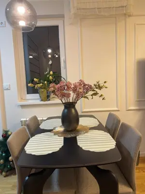 a dining room table with a vase with flowers on it at Stan na dan Bor Apartman in Bor