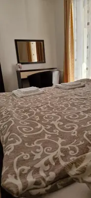 a bed with a brown and white blanket with a mirror at VILA KRUNA Apartments in Kopaonik