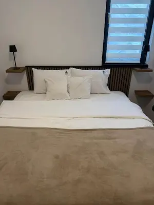 a large bed with white pillows and a window at Apartman IRIS Kopaonik in Kopaonik