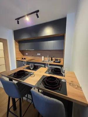 a kitchen with a table with plates and wine glasses at Apartman Raj VV sa garazom in Vrnjci