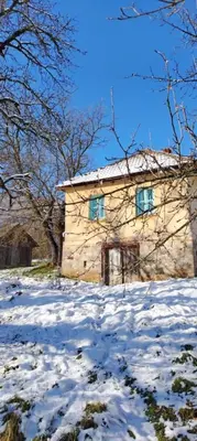 a stone house with blue windows in the snow at Šumarac