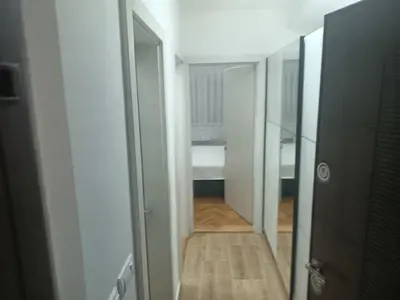 a hallway leading to a room with a door and wooden floor at DA apartman in Vrnjačka Banja