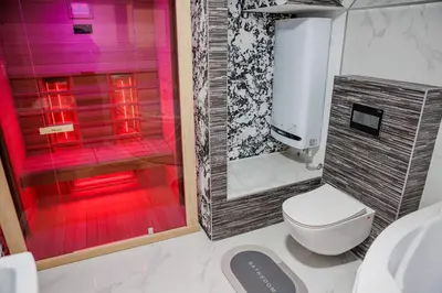 a bathroom with a toilet and a shower with red lighting at Star&spa in Niš