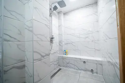 a bathroom with a shower with white marble walls at Vila Vrnjačka Banja in Vrnjačka Banja