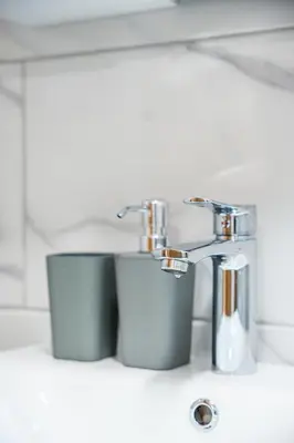 a bathroom sink with a faucet and two cups at Vila Vrnjačka Banja in Vrnjačka Banja