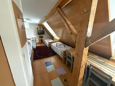 an attic room with two beds and a desk at Konaci Spacious Studio in the Heart of the Slopes in Kopaonik