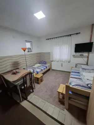 a room with three beds and a table and a tv at PODNOZJe KOPAONIKA in Brus