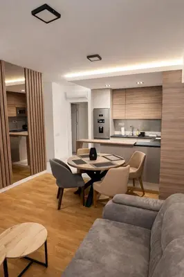 a living room with a table and chairs and a kitchen at Leo Lux 3 in Niš