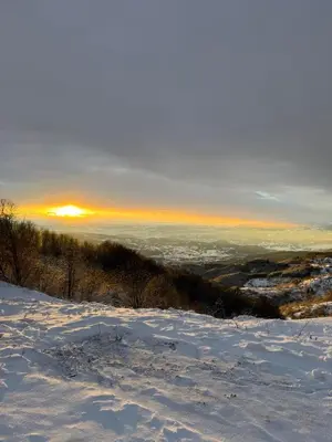 a snow covered hill with the sunset in the background at Sky Nest Kopaonik in Kopaonik