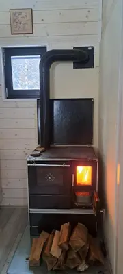 a stove in a room with a pile of wood at Koliba boema in Despotovac