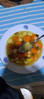 a bowl of soup on a plate with a spoon at Koliba boema in Despotovac