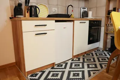 a kitchen with white cabinets and a rug at Apartman Wish Lux in Vrnjci