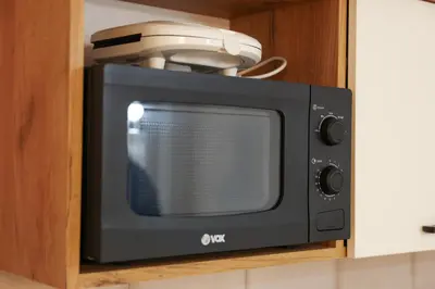 a black microwave sitting on top of a cabinet at Apartman Wish Lux in Vrnjci