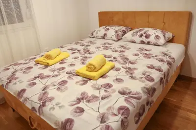 a bed with two yellow slippers on top of it at Apartman Wish Lux in Vrnjci