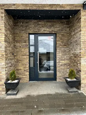 a door to a brick building with two potted plants at Apartman Wish Lux in Vrnjci