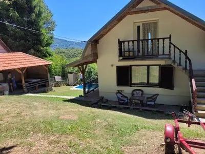 a house with a balcony and two chairs in the yard at Kalina in Vlasina Okruglica