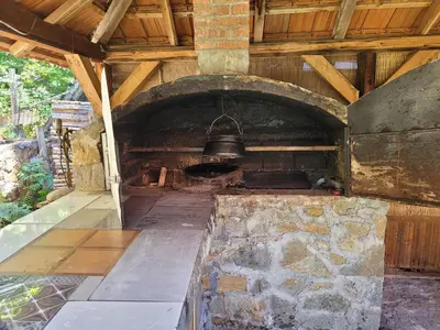 an outdoor oven with a bell hanging from the ceiling at Kalina in Vlasina Okruglica