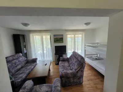 a living room with two chairs and a couch and a bed at Kalina in Vlasina Okruglica