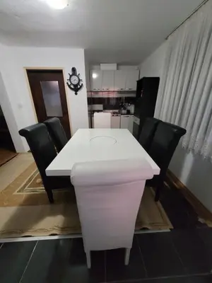 a white table with black chairs and a kitchen at Kalina in Vlasina Okruglica
