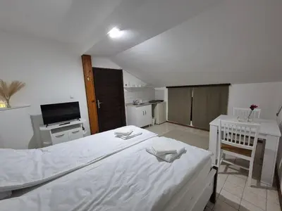 a bedroom with a large white bed and a kitchen at Niš Residence in Niš