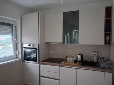 a kitchen with white cabinets and a sink and a window at Onix 1 in Soko Banja