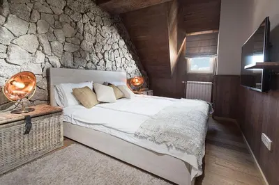 a bedroom with a bed and a stone wall at Top Hill - Župa Kopaonik in Kopaonik