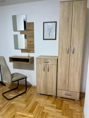 a room with a cabinet and a chair and a mirror at Park Residence 1 in Niš