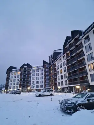 a parking lot with cars parked in the snow at SkyLux Apartments Kopaonik - Residence Hill in Kopaonik