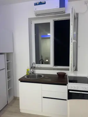a white kitchen with a sink and a window at Saška Apartments in Niš