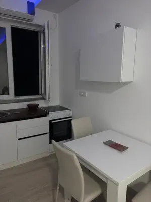 a white kitchen with a white table and chairs at Saška Apartments in Niš